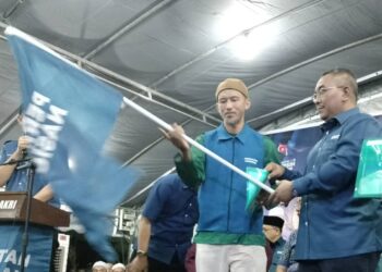 MUHAMMAD SANUSI MD NOR (kanan) menyerahkan dokumen dan bendera parti kepada Unit DUN Mengundi (UDM) semasa melancarkan Jentera Pilihan Raya dan Pengenalan Calon di Markas Tarbiyah Pas Kawasan Bakri.
