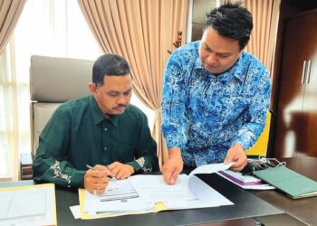 MUHAMAD Radhi Mat Din (kiri) bersama pegawai khasnya, Khairuddin Md. Isa meneliti dokumen berkaitan portfolionya di Wisma Darul Aman, Alor Setar.