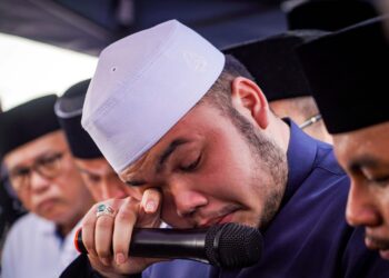 MUHAMMAD Hafiz Naquiddin tidak dapat menahan sebak ketika membacakan talkin di Tanah Perkuburan Raudhatul Sakinah, Taman Selaseh. - UTUSAN/MUHAMAD IQBAL ROSLI
