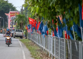 PENGGUNA jalan raya melintasi deretan bendera parti-parti politik yang bertanding pada Pilihan Raya Negeri Kedah di Pekan Kuala Nerang, Kedah. - UTUSAN/ SHAHIR NOORDIN