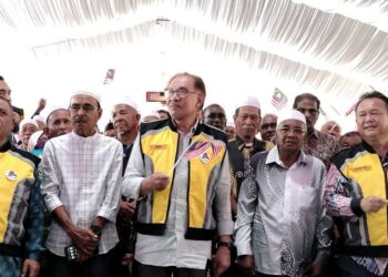 ANWAR Ibrahim memegang Jalur Gemilang bersama bekas pekerja pembinaan Jalan Timur Barat pada pelancaran Kempen MyJalan di Gerik hari ini. - UTUSAN/WAT KAMAL ABAS