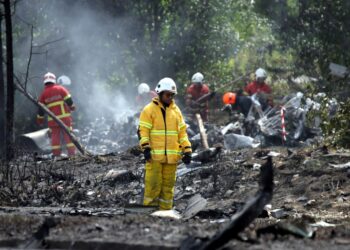 ANGGOTA Bomba dan Penyelamat memeriksa keadaan bangkai pesawat yang hangus terbakar selepas terhempas dan menghentam sebuah motosikal di Elmina, Seksyen U16 Shah Alam, Selangor. -UTUSAN/SADDAM YUSOFF