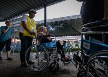 PETUGAS SPR membantu pengundi berkerusi roda untuk menunaikan tanggungjawab mengundi dalam tinjauan hari pengundian sekitar Sepang, Selangor. - UTUSAN/FAIZ ALIF ZUBIR