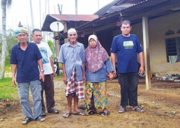 MAHMOD Md. Rejab (tengah) bersama isteri dan anaknya serta penduduk kampung di hadapan rumah lama mereka di Kampung Iboi, Kupang di Baling. -UTUSAN/NORLIA RAMLI