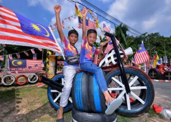 MUHAMMAD Aliff Mazlan, 6, (hadapan) bersama abangnya Muhammad Farhan, 10, bergaya pada rekaan motosikal menggunakan motosikal yang terdapat sebuah rumah di Kampung Sungai Timun, Rembau yang turut dihiasi dengan ratusan Jalur Gemilang sempena sambutan Hari Kebangsaan Ke-66 tahun ini.-UTUSAN/MOHD. SHAHJEHAN MAAMIN.