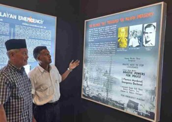 R. Anbananthan (kanan) memberi penerangan kepada pelawat mengenai gambar sejarah pembunuhan pengurus ladang Eropah yang dipamerkan di Galeri dan Monumen Darurat Malaya MPOA di Ladang Sungai Siput. – UTUSAN/SAYED HESHAM IDRIS.