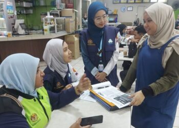 RAFIDAH Abdul Rahim (duduk, kiri) bersama anggota Perkeso yang melakukan pemeriksaan semasa Op Kesan di sekitar pekan Kuah dan Pantai Chenang, Langkawi.
