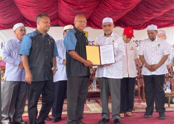 AHMAD Yakub (kanan) menyampaikan surat setuju terima kepada kontraktor pembinaan yang terlibat di tapak Stadium Sukan Bukit Merbau, Selising, Pasir Puteh, Kelantan hari ini. UTUSAN/TOREK SULONG