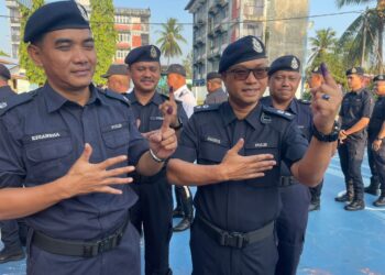 ZAIZUL Rizal Zakaria (kanan) bersama pegawainya menunjukkan jari yang telah dicelup dakwat selepas selesai membuang undi di IPD Pasir Puteh, Kelantan hari ini-UTUSAN/TOREK SULONG