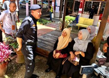 MUHAMAD Zaki Harun (kiri) beramah mesra dengan pengundi yang keluar membuang undi di SMK Agama Falahiah, Pasir Pekan, Tumpat, Kelantan-UTUSAN/ROSLIZA MOHAMED.