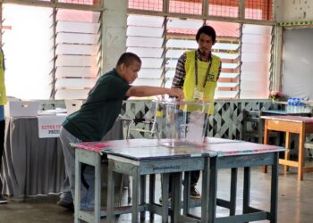 ZIKRILLAH Zairul Akma (kiri) memasukkan kertas undi ke dalam peti selepas selesai memilih di Pusat Mengundi SK Panji di Kota Bharu, Kelantan hari ini. UTUSAN/MUSTAQIM MOHAMED
