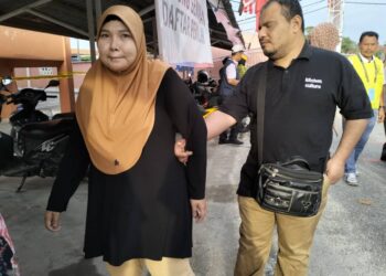 MOHD. Nor Mohd. Din dipimpin isterinya ketika hadir untuk mengundi di Sekolah Menengah Kebangsaan (SMK) Kampung Laut, Tumpat, Kelantan hari ini-UTUSAN/ROHANA ISMAIL.