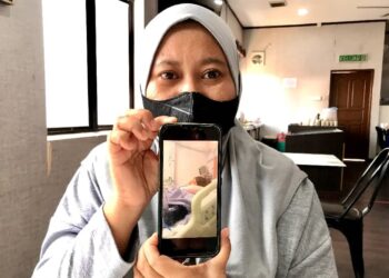 ZURAIDAH Abd. Aziz  menunjukkan gambar Nurul Aqilah yang sedang menerima rawatan di HRPZ II Kota Bharu Kelantan.- UTUSAN/ROSLIZA MOHAMED