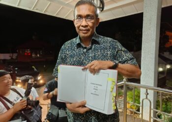 TAKIYUDDIN Hassan menunjukkan buku perlembagaan Undang-Undang Tubuh Kerajaan Negeri Kelantan selepas menghadiri mesyuarat Pas Pusat dan Pas Kelantan di Kota Bharu, Kelantan malam tadi-UTUSAN/YATIMIN ABDULLAH