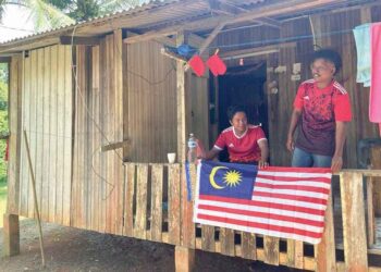 MOHD. Nizam Zainal (kiri) mengibar Jalur Gemilang di rumahnya
di Pos Tohoi, Gua Musang, Kelantan. – UTUSAN/AIMUNI TUAN LAH