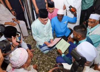 ANWAR Ibrahim membantu saudara baharu, Muhammad Anuar Karthiban, 27, melafazkan dua kalimah syahadah selepas menunaikan solat Jumaat di Masjid Jamek Ar - Rahimiah. -UTUSAN/SADDAM YUSOFF