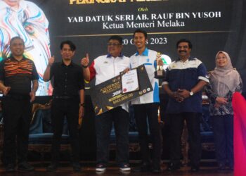 AB. RAUF Yusoh menyampaikan hadiah kepada Mohammad Fiza Mohd. Daud yang dinobatkan sebagai penerima Anugerah Belia Perdana kategori lelaki sempena sambutan HBN23 di Kompleks Sukan Masjid Tanah, Alor Gajah, Melaka. - UTUSAN/AMRAN MULUP