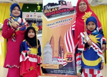 NOOR Hasliza Mohd. Ghazali (belakang, kanan) bersama Siti Khalidah Mohd. Banod dan dua murid mengenakan busana Jalur Gemilang di Sekolah Kebangsaan Felda Kota Gelanggi Dua di Jerantut, Pahang. - UTUSAN/HARIS FADILAH AHMAD