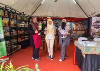 SABARIAH MUSA (kanan) menunjukkan produk IKS yang dijual di reruai daerah Kota Tinggi sempena Festival Majestic Johor di Puteri Harbour.