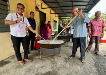 ABDUL RAMLI (kiri) membantu mengacau bubur Asyura sewaktu turun padang ke Dewan Orang Ramai Kampung Kandis, Jerlun, hari ini. -UTUSAN/ASYRAF MUHAMMAD