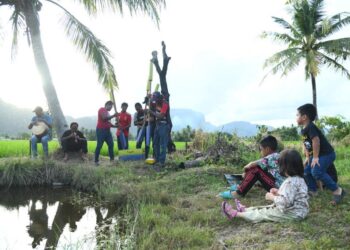 SEKUMPULAN kanak-kanak menyaksikan 
persembahan alu bunyi iaitu kesenian dan warisan Perlis berusia lebih 200 tahun yang terus bertahan di kawasan sawah padi berlatar belakangkan bukit di Kampung Nesam, Bintong, Kangar, Perlis, semalam.- UTUSAN/IZLIZAN OTHMAN