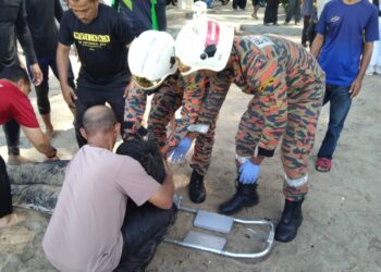 ANGGOTA bomba memberikan rawatan awal kepada mangsa kejadian bot terbalik di Pantai Teluk Batik, Lumut hari ini. - UTUSAN/IHSAN JBPM