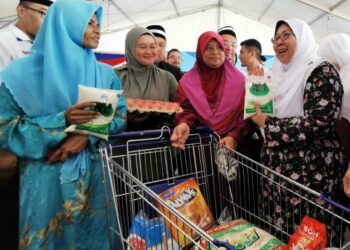 FUZIAH Salleh (kanan) beramah mesra dengan pengunjung Program Jelajah Jualan Rahmah peringkat negeri Terengganu di Kuala Ibai, Kuala Terengganu, hari ini. - UTUSAN/KAMALIZA KAMARUDDIN