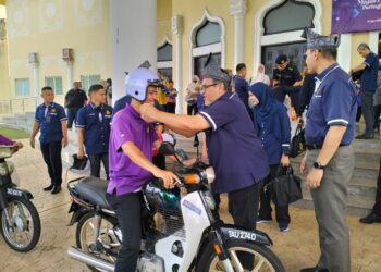 HASBI Habibollah (dua dari kanan) memakaikan topi keledar kepada penerima lesen program MyLesen B2 di Kuala Terengganu, hari ini. - UTUSAN/KAMALIZA KAMARUDDIN