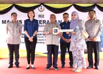 SAARANI Mohamad (tengah) menyerahkan replika kunci kepada pembeli  projek Rumah Perakku, Noor Hushila Nayan di Sitiawan, Lumut hari ini. - UTUSAN/MUHAMAD NAZREEN SYAH MUSTHAFA