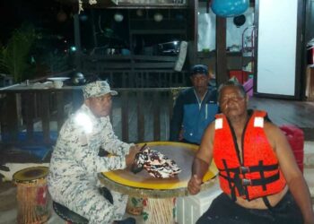 SEORANG anggota Maritim Malaysia bersama dua nelayan yang selamat selepas bot gentian kaca dinaiki mereka terbalik
di perairan Pulau Kapas di Marang, semalam.