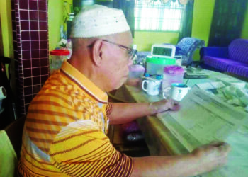 NASARUDIN MOHD. JADAN melihat slip bayaran bulanan daripada Felda yang dipotong sehingga menjejaskan pendapatan mereka di Felda Tenang, Segamat.