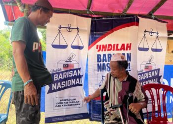 RAHMAD Anjang (kiri) menghias sebuah pondok dengan bendera BN kawasan di Pos Pulat, Gua Musang, Kelantan. - MINGGUAN/AIMUNI TUAN LAH