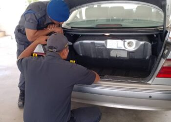 ANGGOTA penguatkuasa KPDN memeriksa tangki minyak kereta yang diubahsuai selepas menahan seorang lelaki di sebuah stesen minyak di Pengkalan Hulu, semalam.  - UTUSAN/IHSAN KPDN