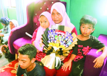 NAZATUL Shazwati Sulaiman (tengah) bersama anaknya memegang hadiah hari jadi diberikan arwah suaminya, Mohd. Ridhwan Mahayudin di Felda Lepar Utara 1 di Maran, Pahang. – UTUSAN/SALEHUDIN MAT RASAD
