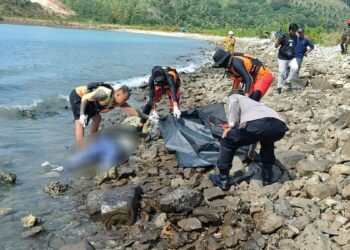 POLIS memeriksa keadaan mayat tanpa kepala yang ditemukan di tepi pantai di Lampung. - AGENSI