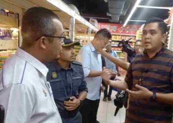 MUHAMAD Saleh memperkatakan sesuatu selepas membuat pemeriksaan beras dalam Ops Jamin di sebuah pasaraya di Jasin, Melaka. UTUSAN/AMRAN MULUP