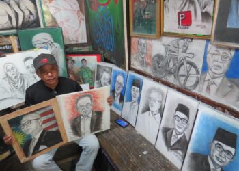 RIDZWAN Abdul Wahab menunjukkan koleksi lukisan potret wajah Perdana Menteri di Kampung Bertam Baru, Gua Musang, Kelantan. – UTUSAN/AIMUNI TUAN LAH