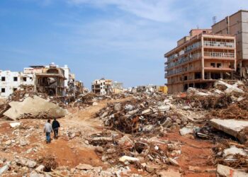 DUA lelaki berjalan di atas runtuhan bangunan yang musnah disebabkan banjir besar di bandar Derna, timur Libya. - AFP