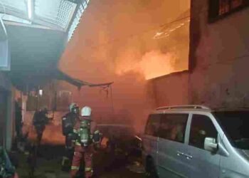 ANGGOTA bomba memadamkan kebakaran bengkel membaiki kereta di Taman Kota Besar yang dijilat api dalam kejadian awal pagi tadi.