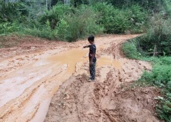 SEORANG penduduk Orang Asli menunjukkan kerosakan jalan yang berlaku menuju ke perkampungan Orang Asli Pos Bihai, Gua Musang, Kelantan. – UTUSAN/AIMUNI TUAN LAH