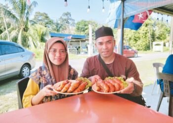 AHMAD FUAD YUSOF dan Siti Ashakinah menunjukkan masakan berasaskan udang galah yang dijual di Warung Gorgon di Kampung Tanjung Air Hitam, Pontian.