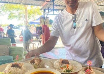 SEORANG pengunjung menunjukkan nasi dagang di kedai Nasi Dagang Atas Tol, Kuala Terengganu. - UTUSAN/KAMALIZA KAMARUDIN