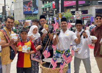 KAKITANGAN Restoran nasi kandar tertua negara, Restoran Hameediyah ketika mengedarkan 100 bungkus nasi kandar percuma di sekitar Bukit Bintang, Kuala Lumpur sempena Hari Malaysia baru-baru ini.