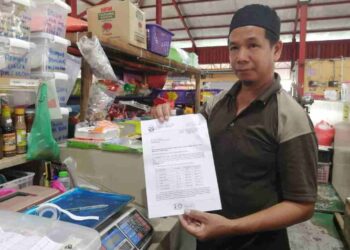 ANUAR Zaini Mohd. menunjukkan surat pemakluman kenaikan kadar sewa  di Pasar Baru Wakaf Tapai, Marang, semalam. - UTUSAN/NOOR HAYATI MAMAT