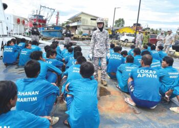 KHAIRUN Dalilah Baharin (tengah) membuat pemeriksaan penahanan nelayan asing Vietnam di Pejabat Maritim Malaysia di Tok Bali, Pasir Puteh, Kelantan, semalam. - UTUSAN/TOREK SULONG