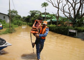 ANGGOTA Angkatan Pertahanan Awam (APM) Kota Setar mendukung seorang kanak-kanak yang terperangkap ke pusat pemindahan sementara di Kampung Bukit, Mukim Derang. Pokok Sena semalam. 
– UTUSAN/SHAHIR NOORDIN