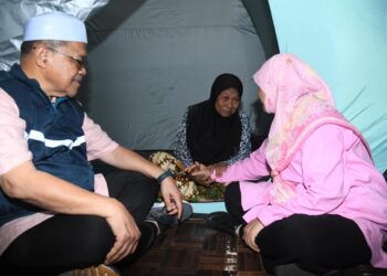 SHAHIDAN Kassim dan isterinya, Shamsiah Yasin menyantuni seorang warga emas di
PPS SK Arau, Perlis, semalam.- UTUSAN/IZLIZAN OTHMAN