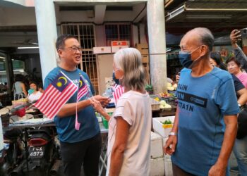 DOMINIC Lau ketika mengedarkan Jalur Gemilang kepada orang ramai di pasar pagi Sungai Ara, Pulau Pinang, hari ini.