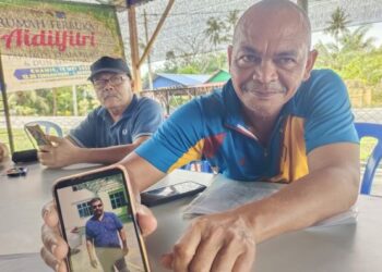 KAMARUDIN Mansor menunjukkan gambar abangnya, Rosli Mansor yang menghilangkan diri tanpa khabar berita sejak lebih lima tahun lalu. - UTUSAN/NOR AINNA HAMZAH