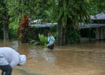 SEORANG penduduk meredah banjir yang hampir mencecah paras pinggang selepas melihat keadaan rumahnya di Kampung Paya Nongmi, Changlun di Kubang Pasu. -UTUSAN/SHAHIR NOORDIN